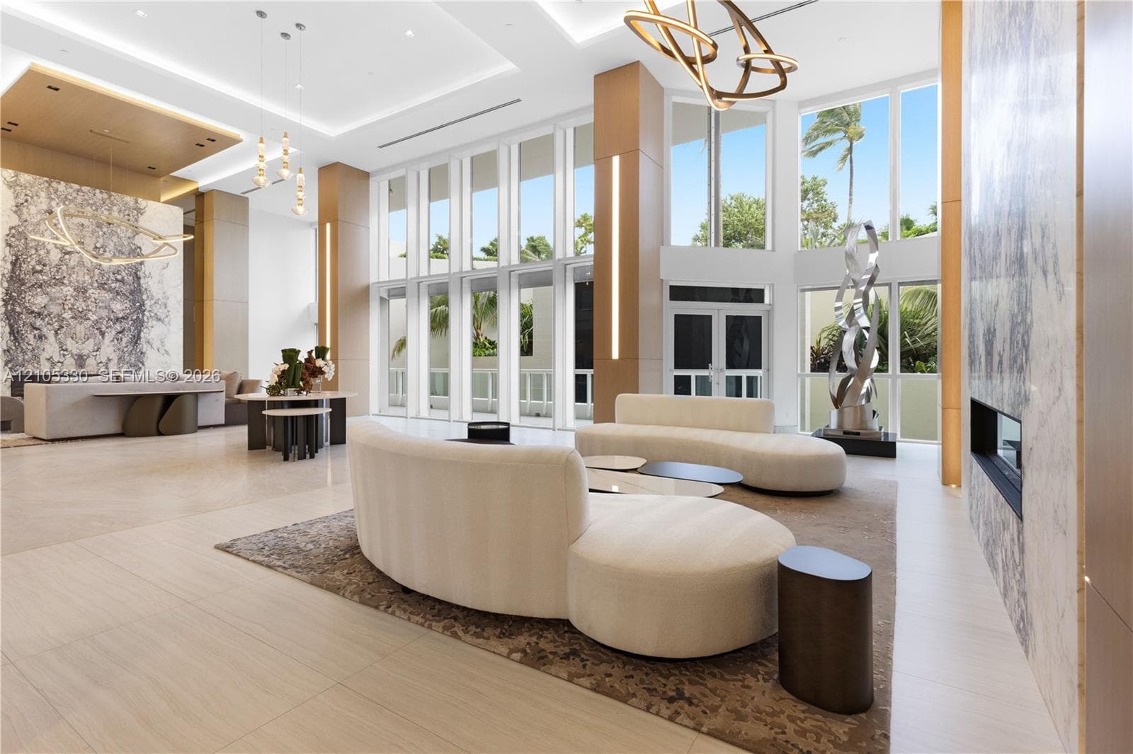 Expansive double-height windows, a large format stone accent wall, recessed lighting, and a linear electric fireplace