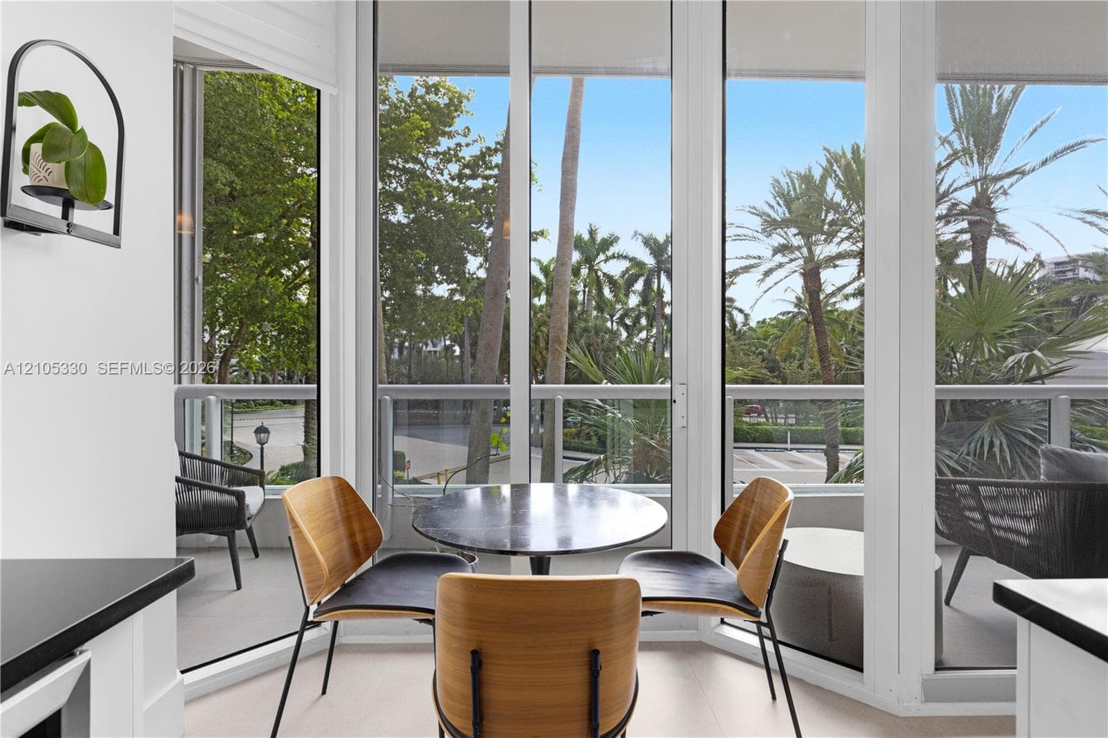 Full-height glass panels, white interior walls, and a balcony with a glass railing