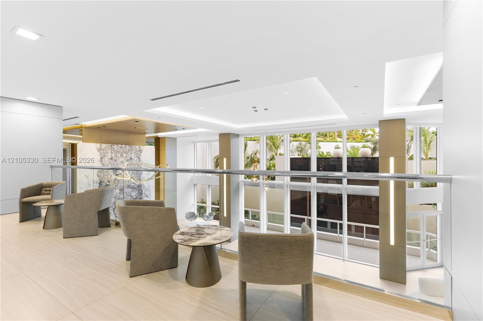 Upper-level lounge area with light wood-finish flooring, recessed lighting, and a glass railing system