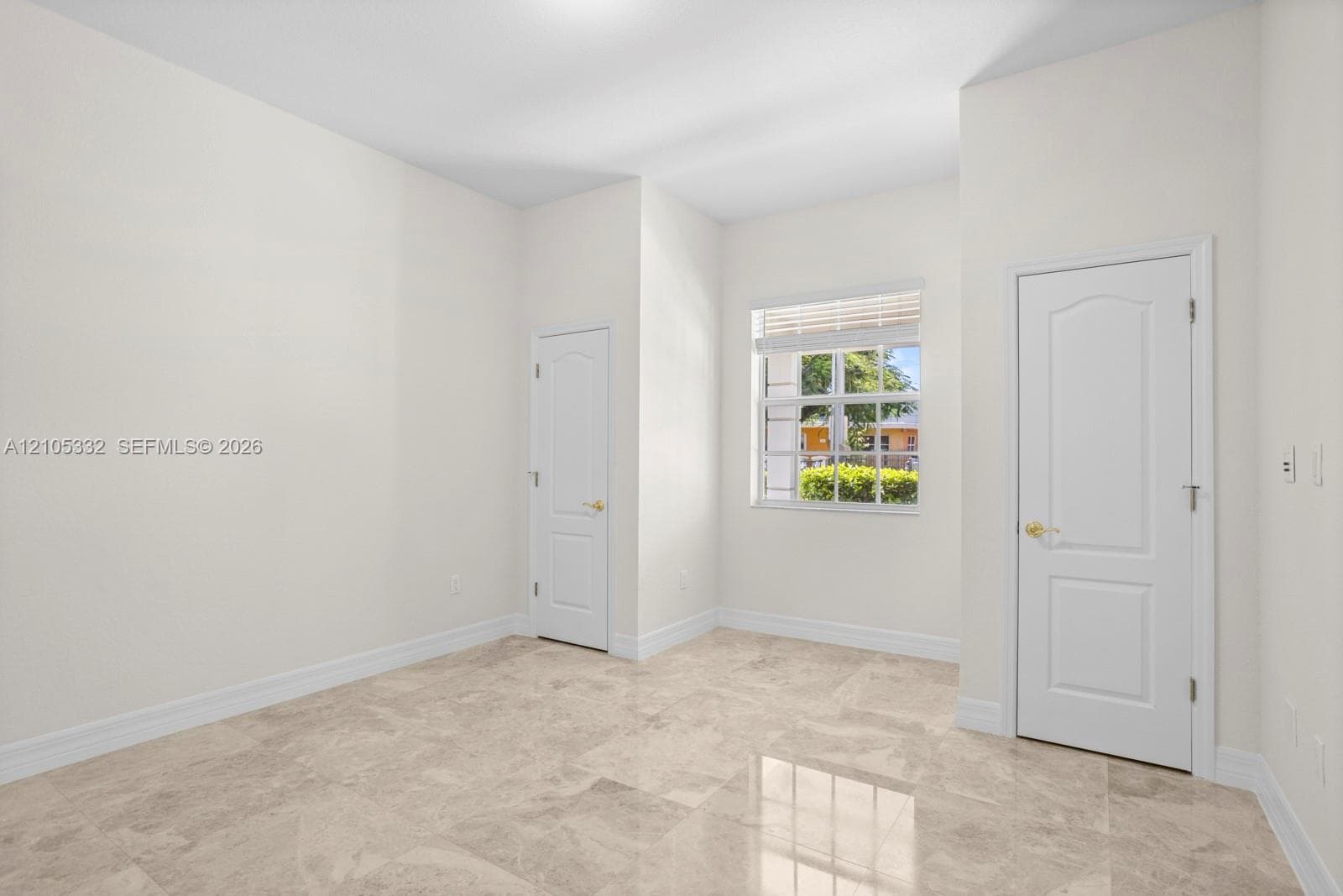 Neutral-toned tile flooring, white interior walls, white two-panel interior doors, and a window with horizontal blinds