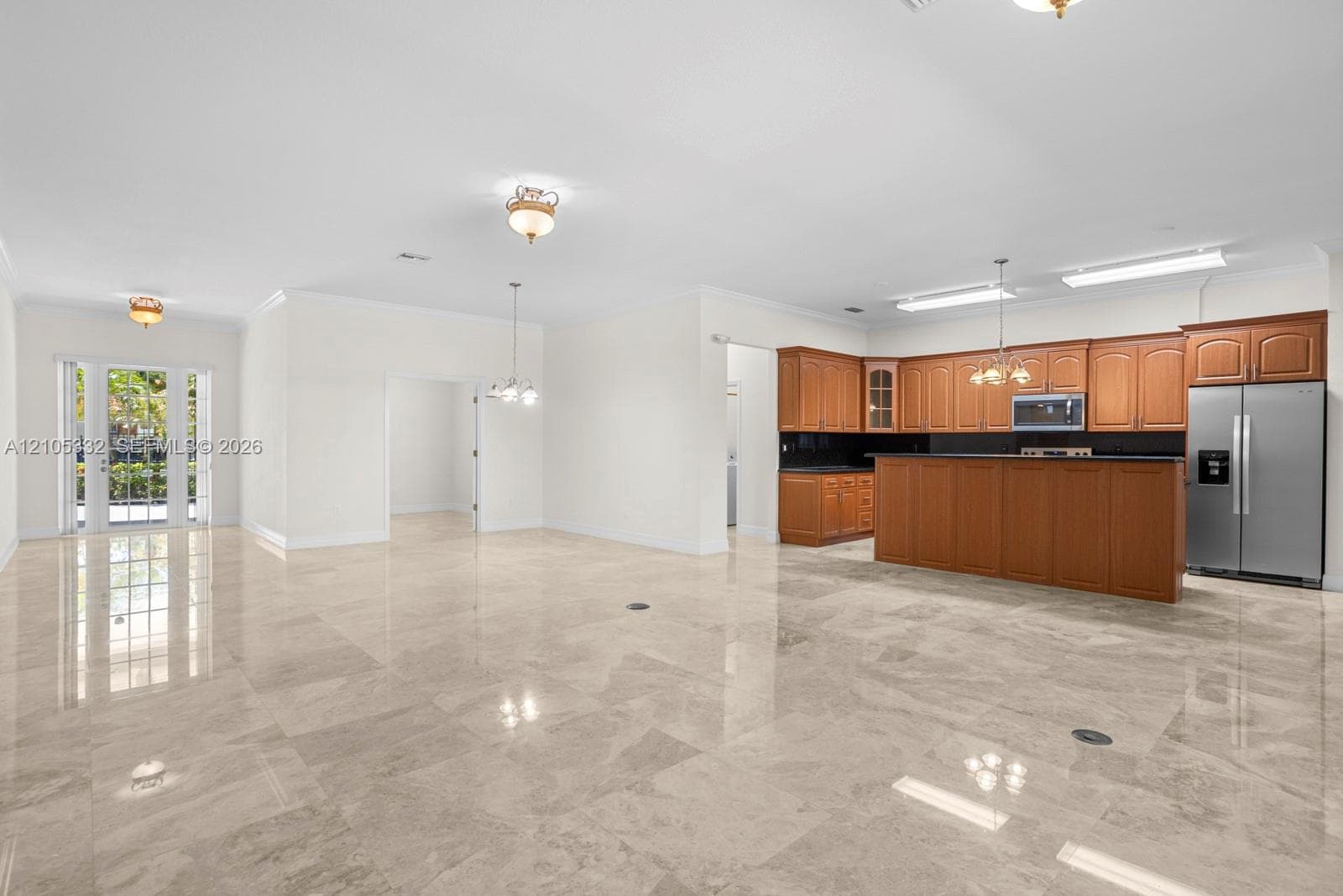 Polished stone-finish flooring throughout, kitchen featuring wood cabinetry and stainless steel appliances, and French doors providing outdoor access