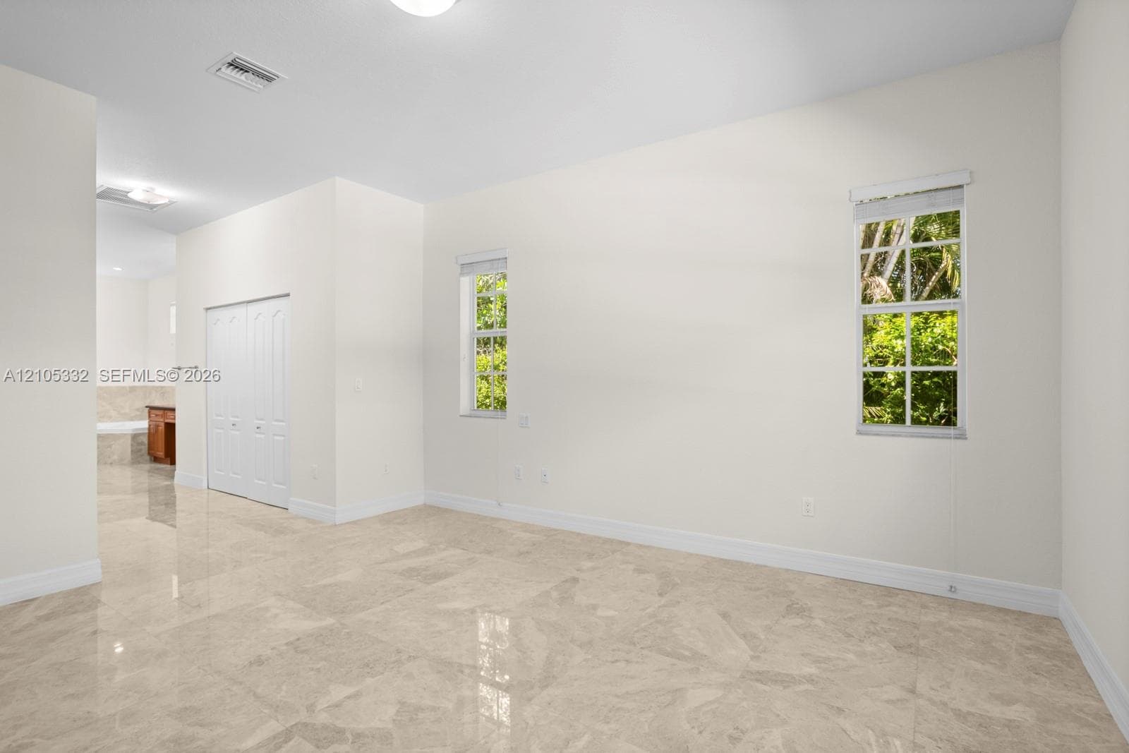 Polished tile flooring, two windows with roller shades, recessed lighting, and bifold closet doors