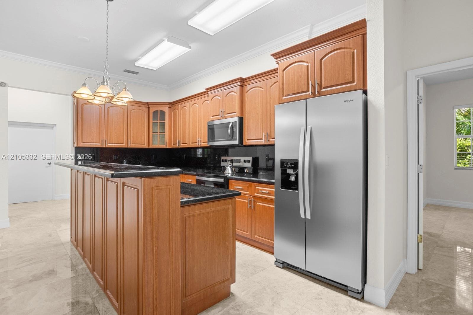 Kitchen featuring wood cabinetry, stainless steel appliances, dark countertops, a breakfast bar, and tile flooring