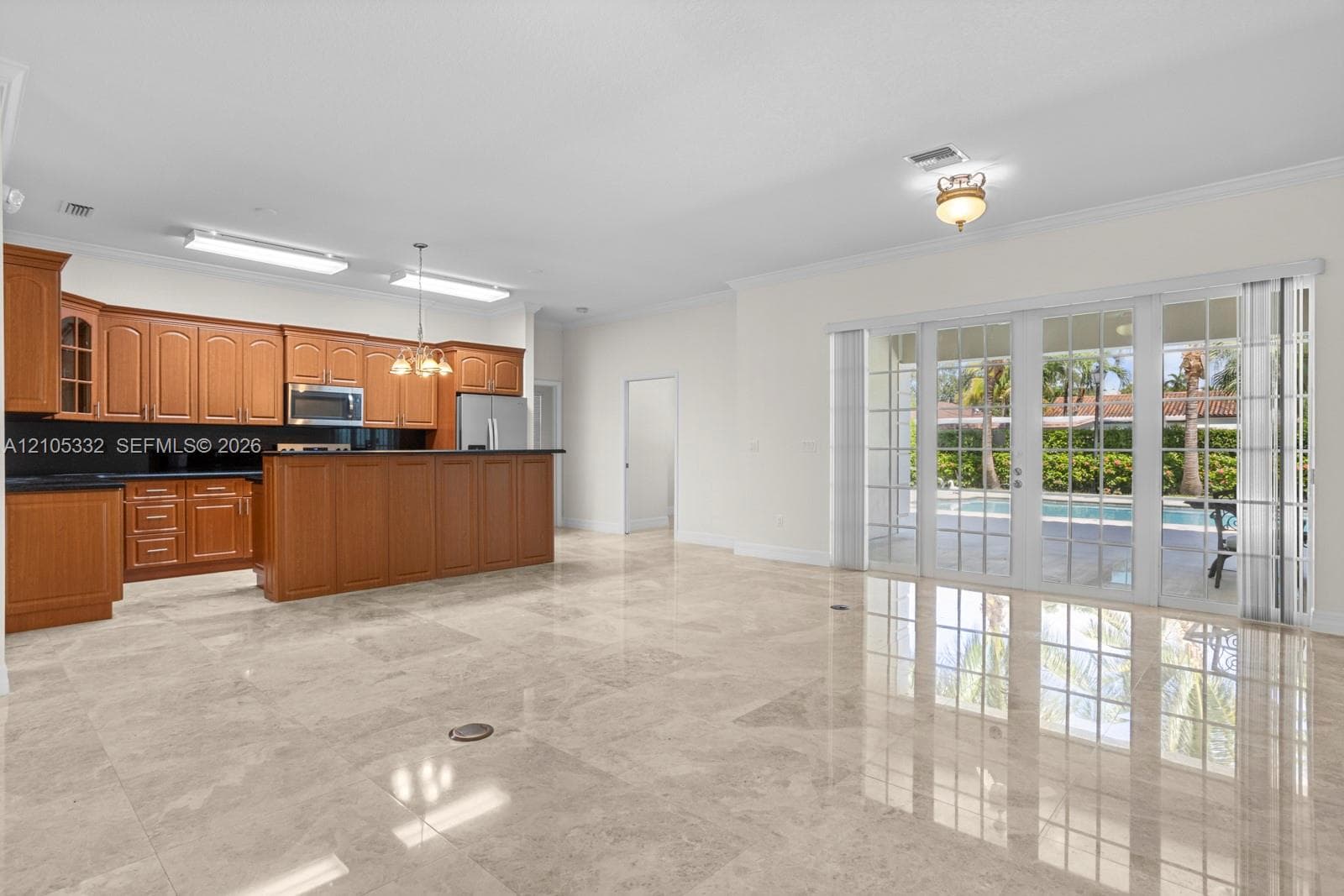 Tile flooring, wood-finish cabinetry, built-in stainless steel appliances, breakfast bar, and bifold glass doors