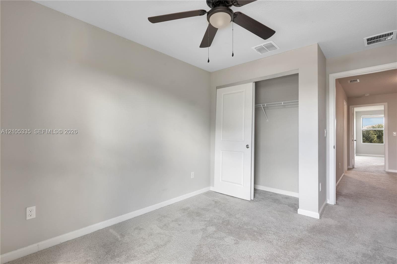Plush carpeting, neutral wall tones, and a ceiling fan with integrated lighting