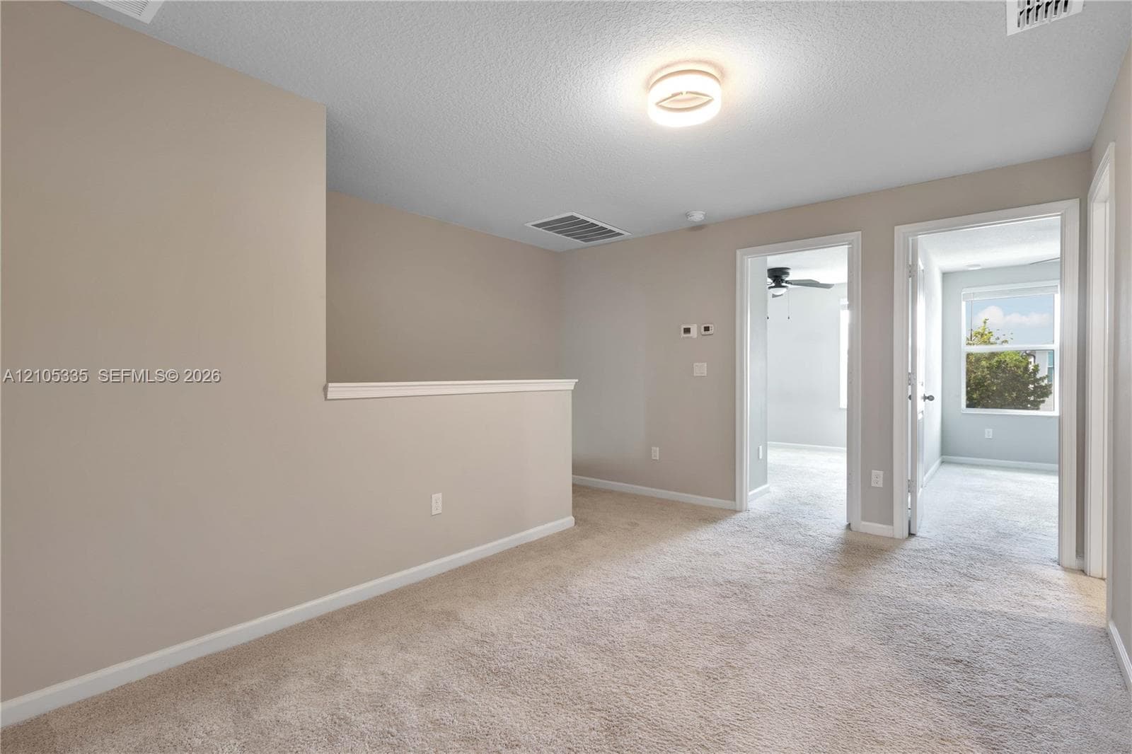 Carpeted loft area with two white interior doors, a partial wall, and a flush mount ceiling light fixture