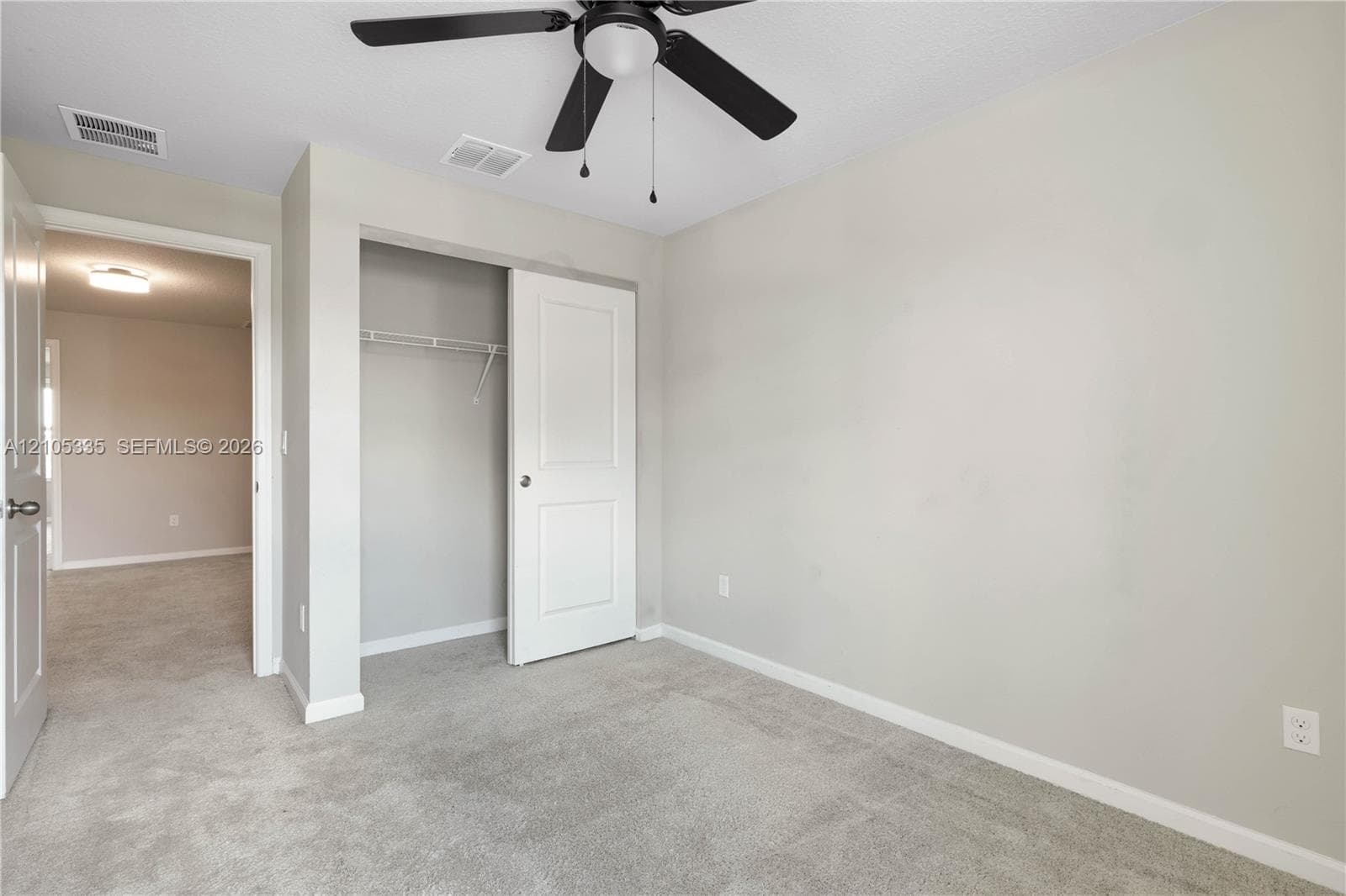 Carpeted room featuring a ceiling fan, closet with bi-fold doors, and a wire shelving system
