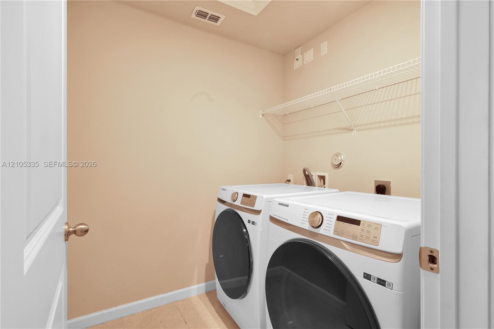Laundry area featuring a wire shelving unit, light-toned wall paint, and light wood-finish flooring