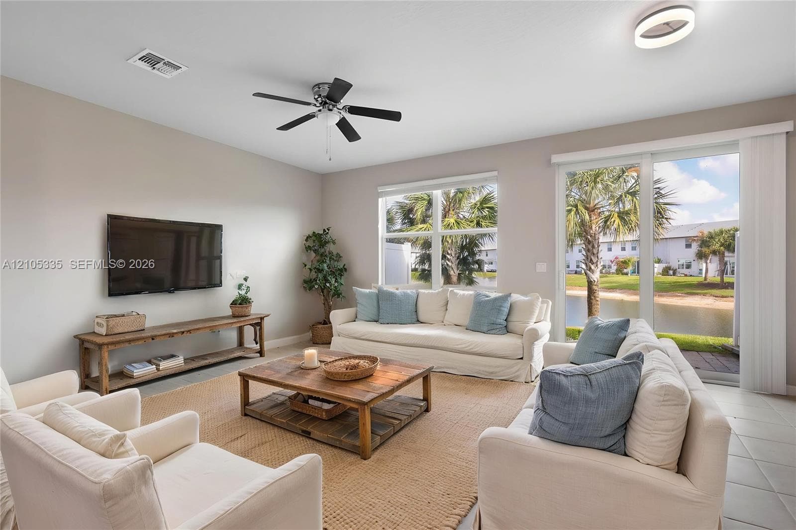 Spacious living area featuring large windows, sliding glass door access to the exterior, and a ceiling fan