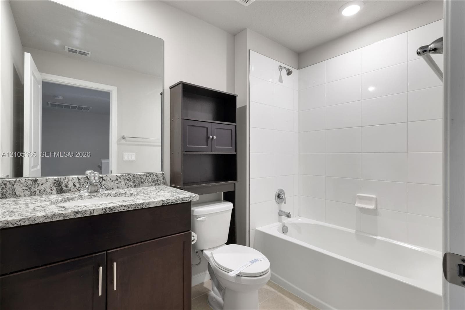 Vanity with a speckled countertop, dark wood-finish cabinetry, and an integrated sink