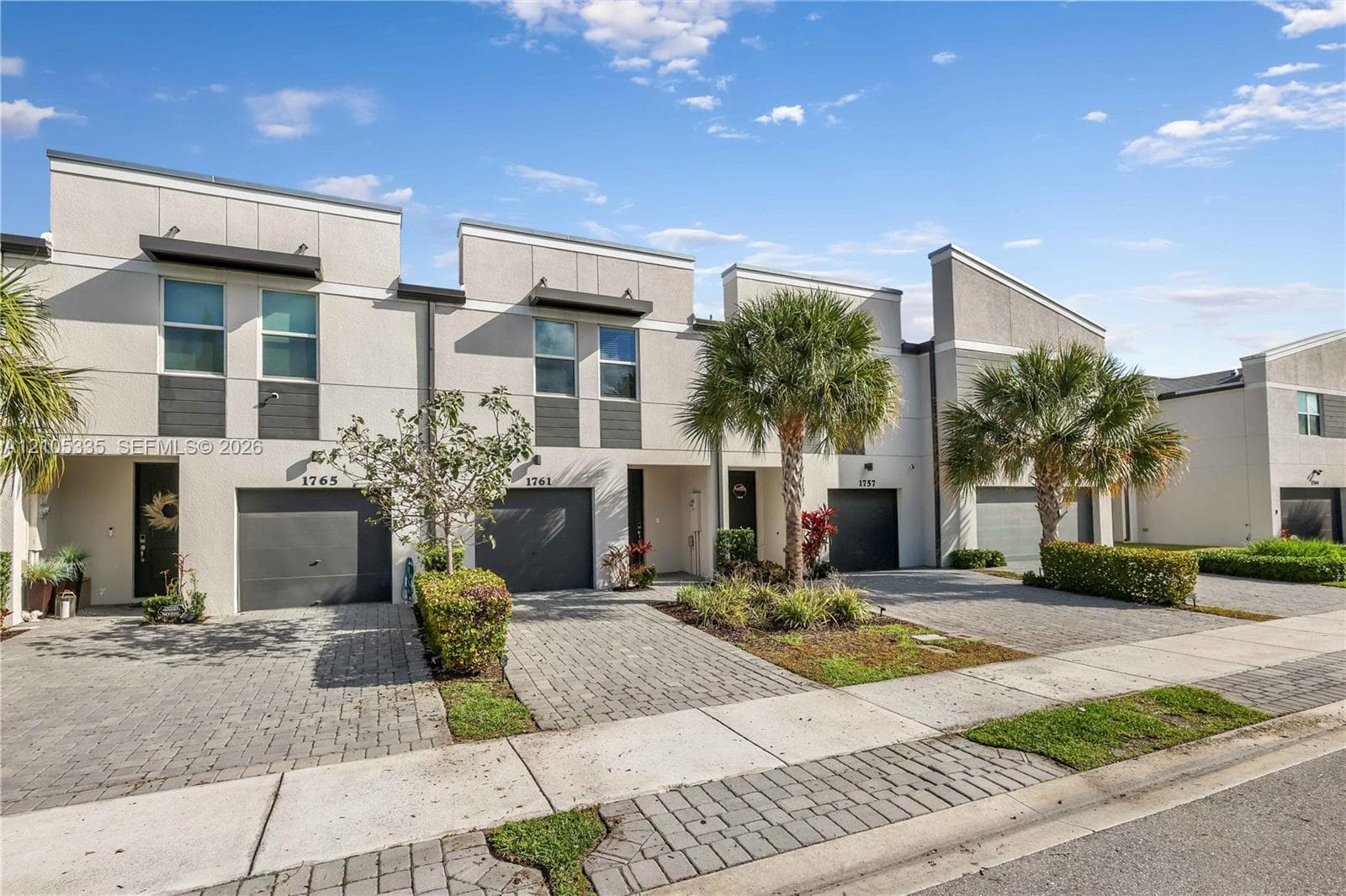 Modern townhome with a stucco exterior, integrated garage, and a paver driveway