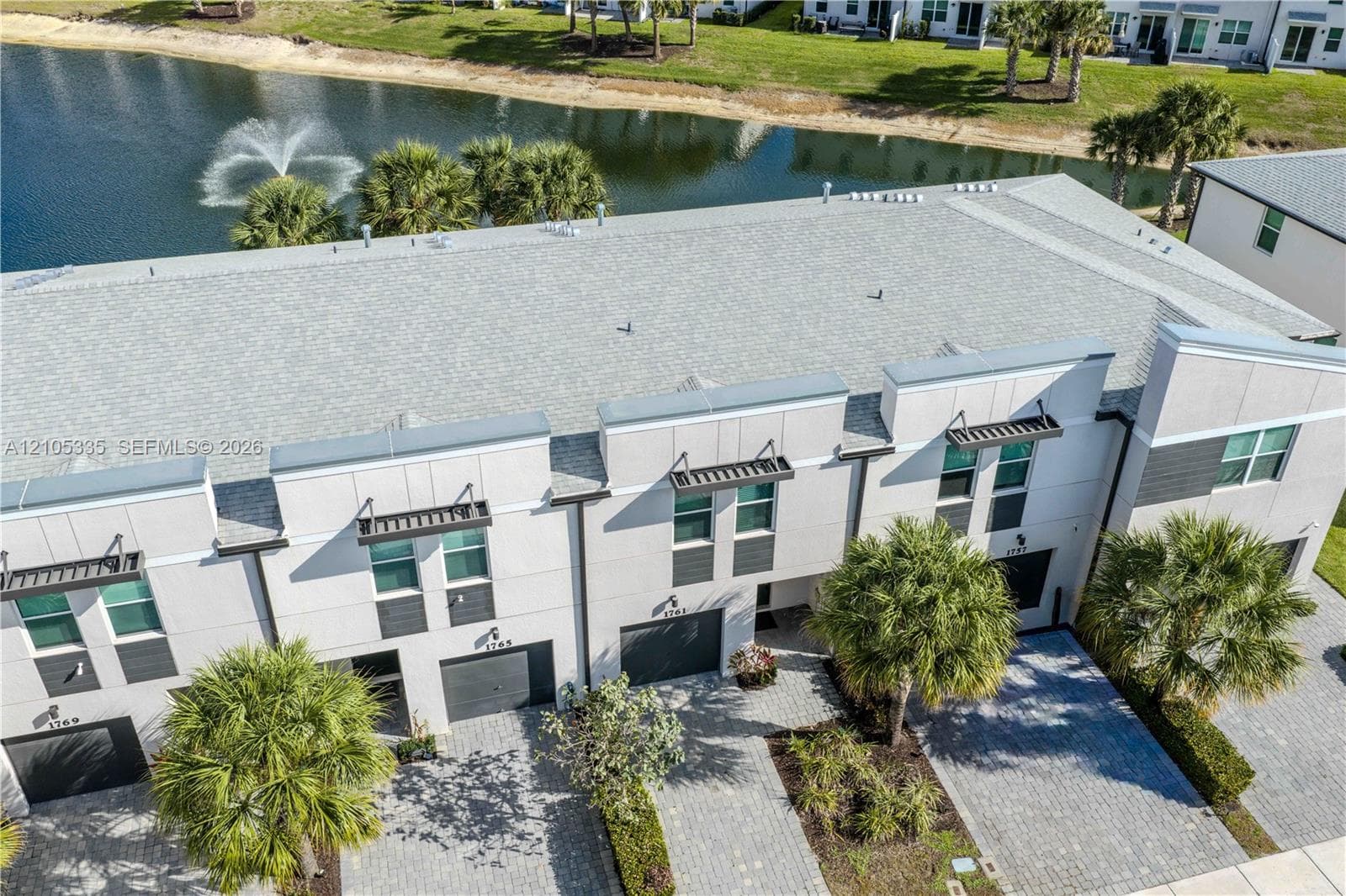 Modern townhome exterior featuring an attached garage, paver driveway, and contemporary architectural elements