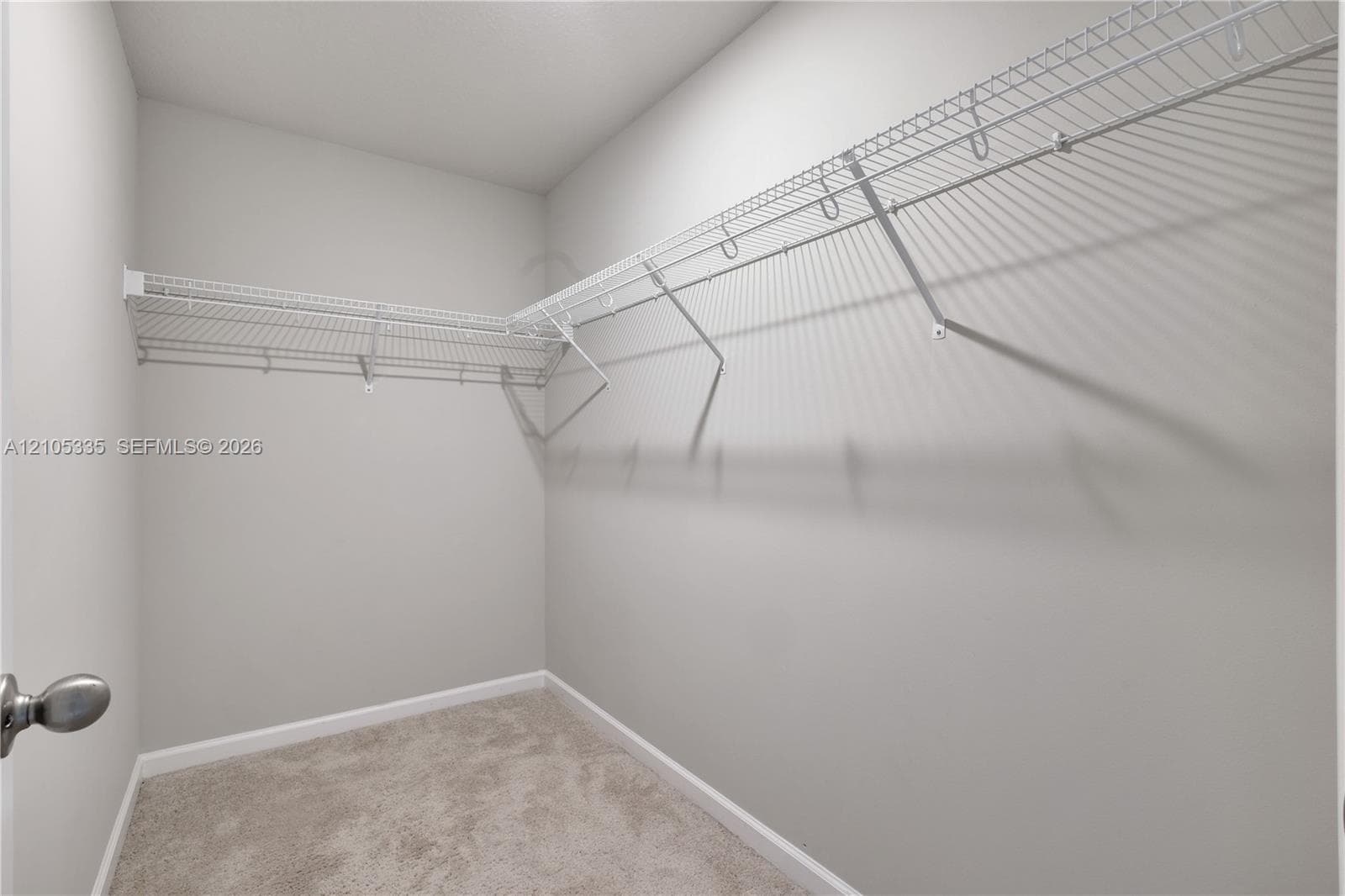 Neutral gray wall paint, light-colored carpet, and white wire shelving system