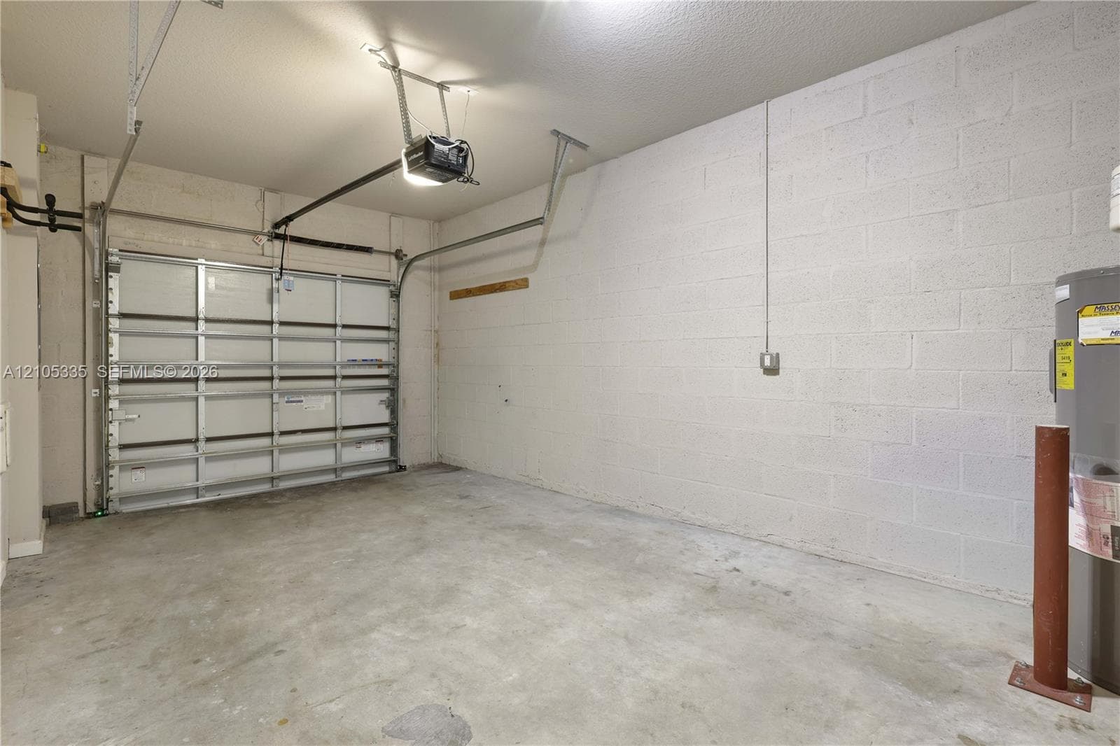 Garage with a concrete floor, white block walls, and an overhead garage door opener