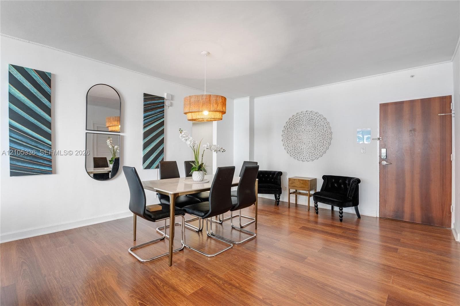 Open interior space featuring wood-finish flooring, a drum pendant light fixture, and a solid-core wood-veneer entry door