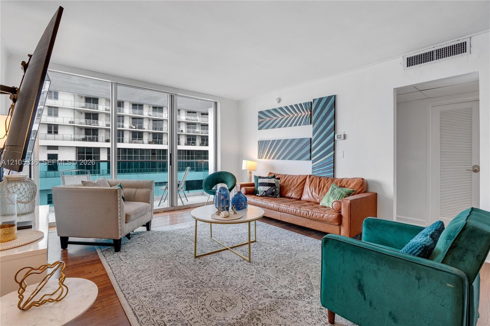 Floor-to-ceiling windows, wood-finish flooring, and sliding glass doors providing outdoor access