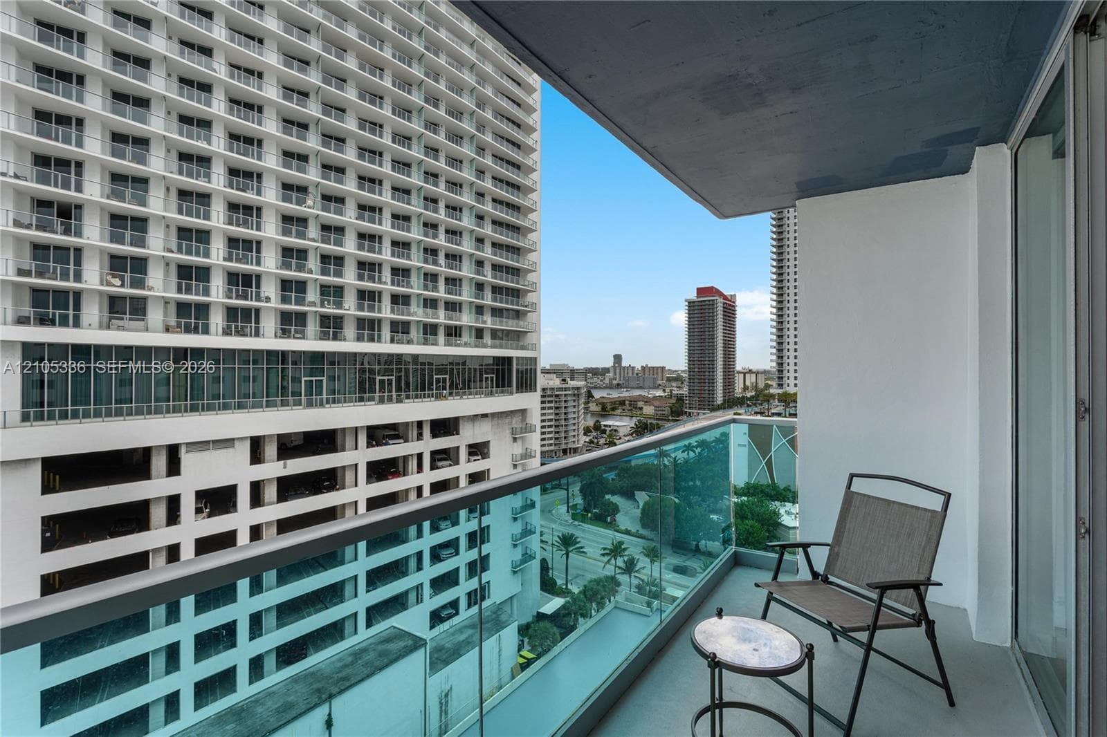 Private balcony featuring glass panel railing, concrete flooring, and an elevated cityscape backdrop