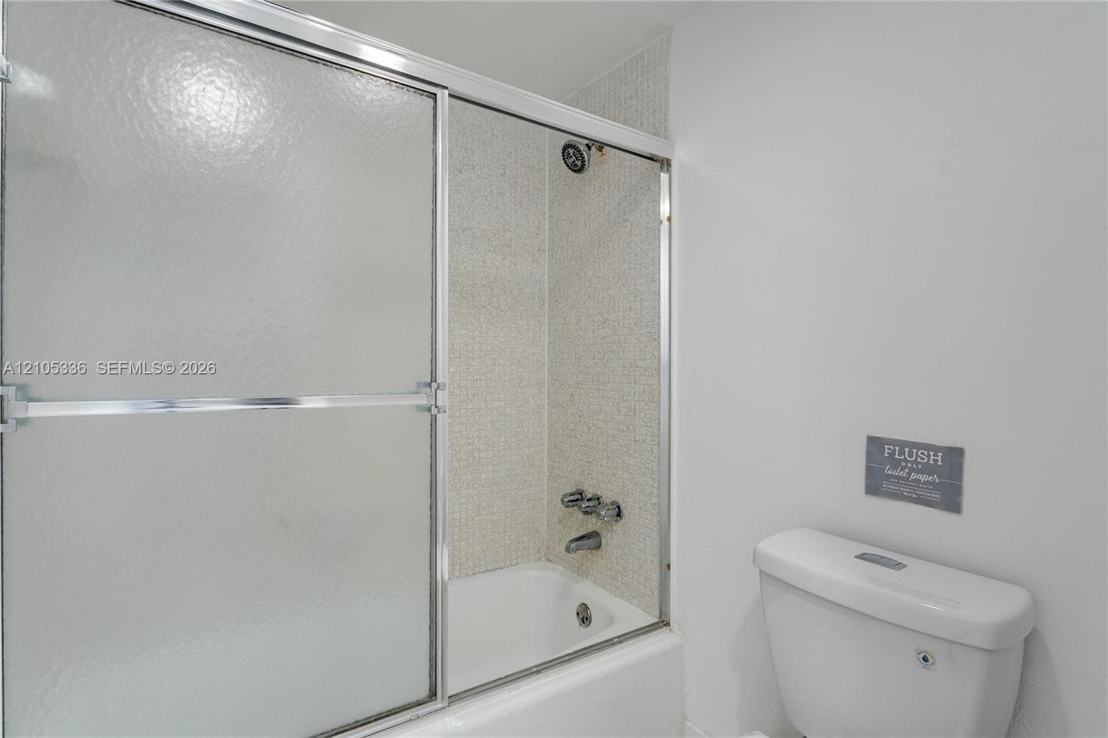 Bathtub featuring a glass sliding enclosure, chrome fixtures, and patterned wall tile