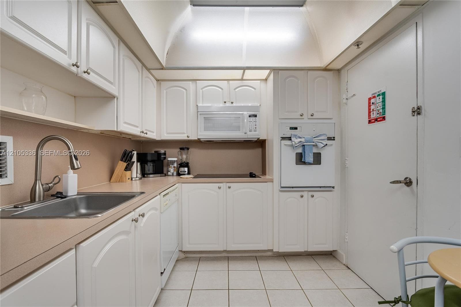 Kitchen featuring white cabinetry, built-in wall oven, integrated microwave, solid surface countertops, and ceramic tile flooring
