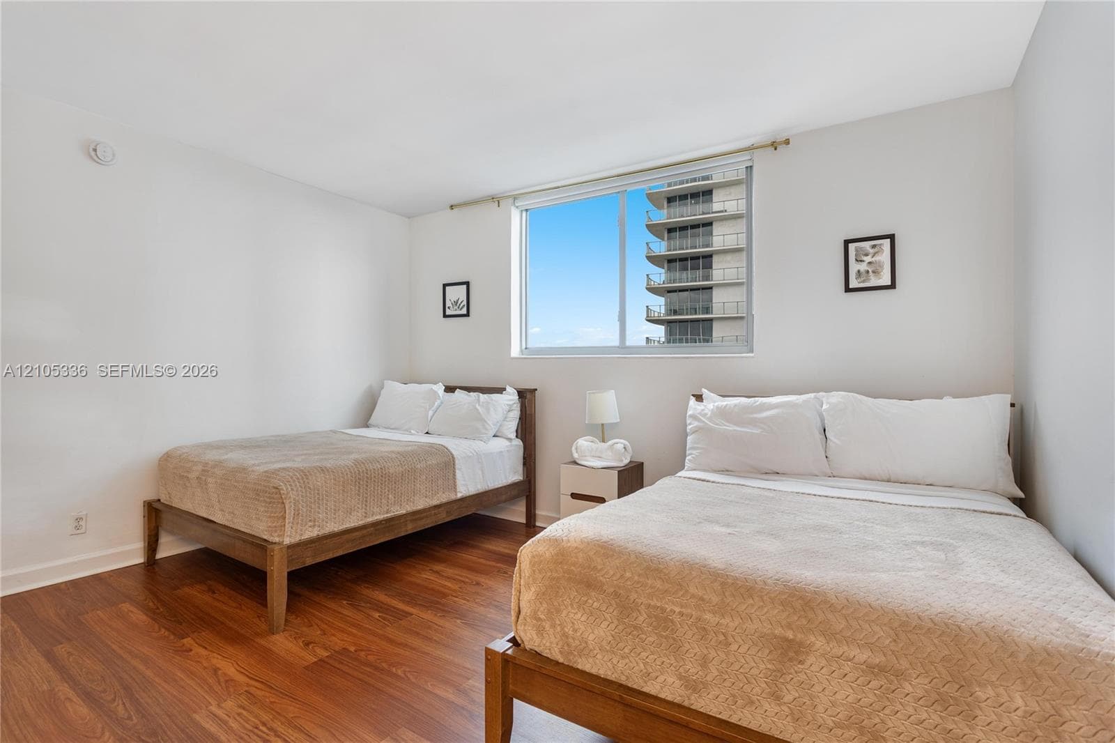 Bedroom featuring wood-finish flooring, neutral walls, and a large window with a metal curtain rod