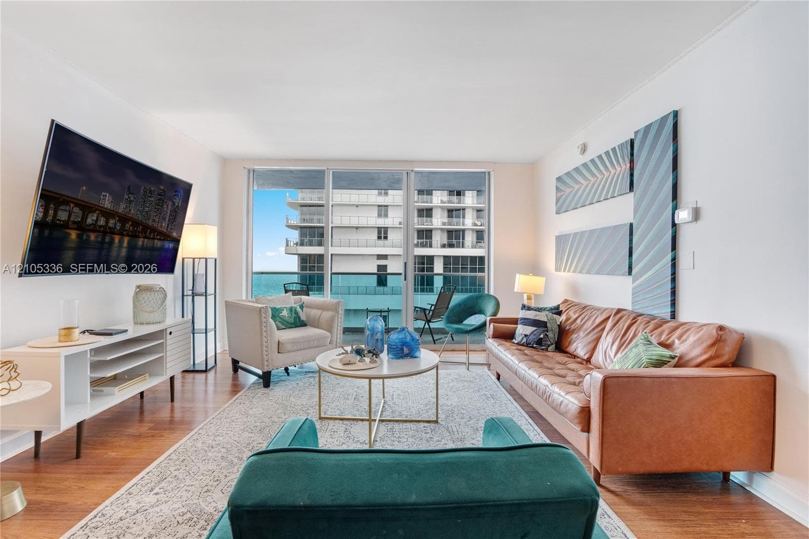Living area featuring wood-finish flooring and floor-to-ceiling glass sliding doors opening to a balcony
