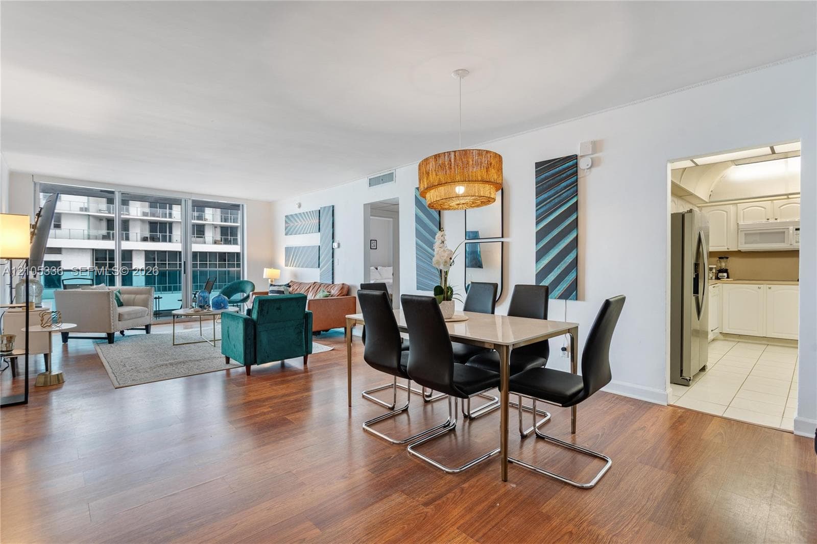 Open-concept interior featuring wood-finish flooring, floor-to-ceiling glass sliding doors, and a multi-tiered circular pendant light
