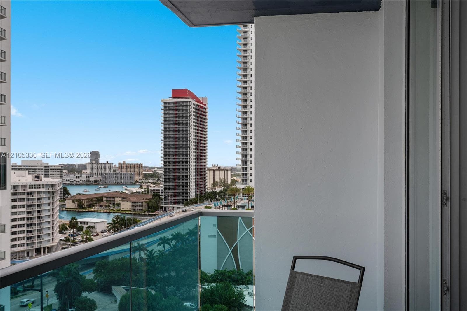 Private balcony with glass panel railing overlooking urban skyline and coastal waterway