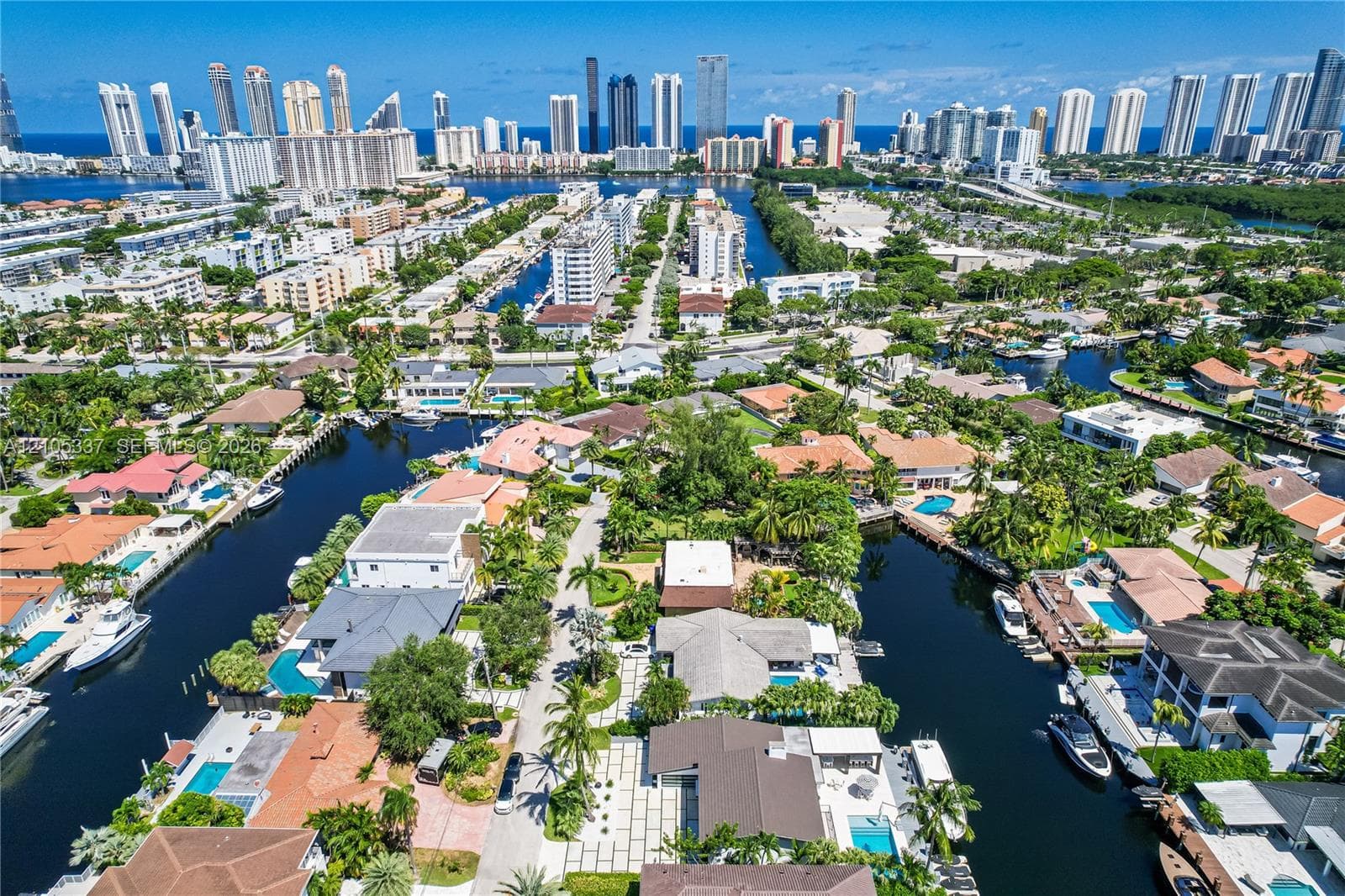 Aerial perspective featuring deep-water canal access, private boat dockage, paved multi-vehicle driveway, swimming pool, and tropical landscaping