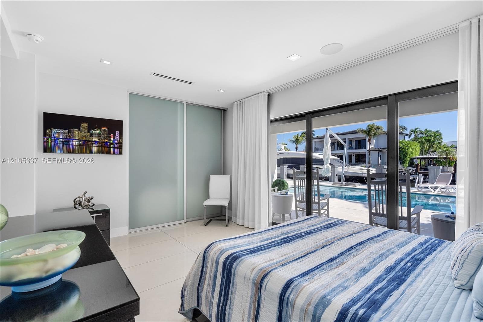 Large-format ceramic floor tiling, floor-to-ceiling glass sliding doors, recessed lighting, and built-in sliding panel closet doors