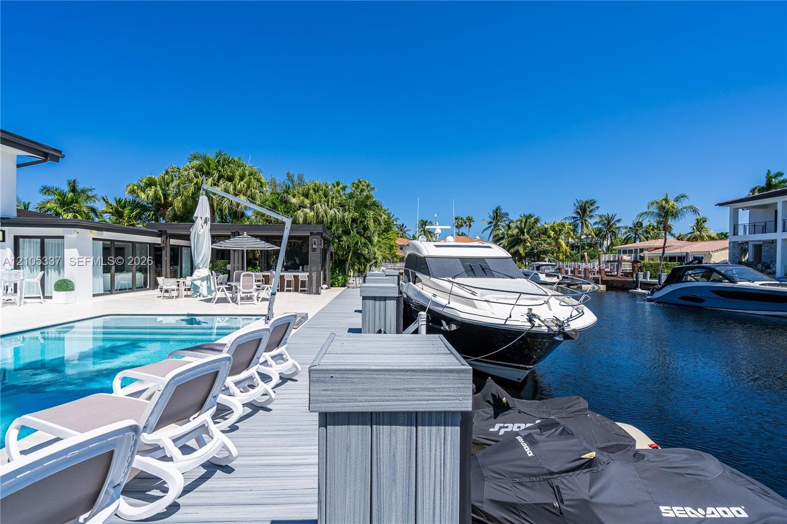 Waterfront deck with composite wood-finish decking, private boat slip, and concrete-bordered swimming pool