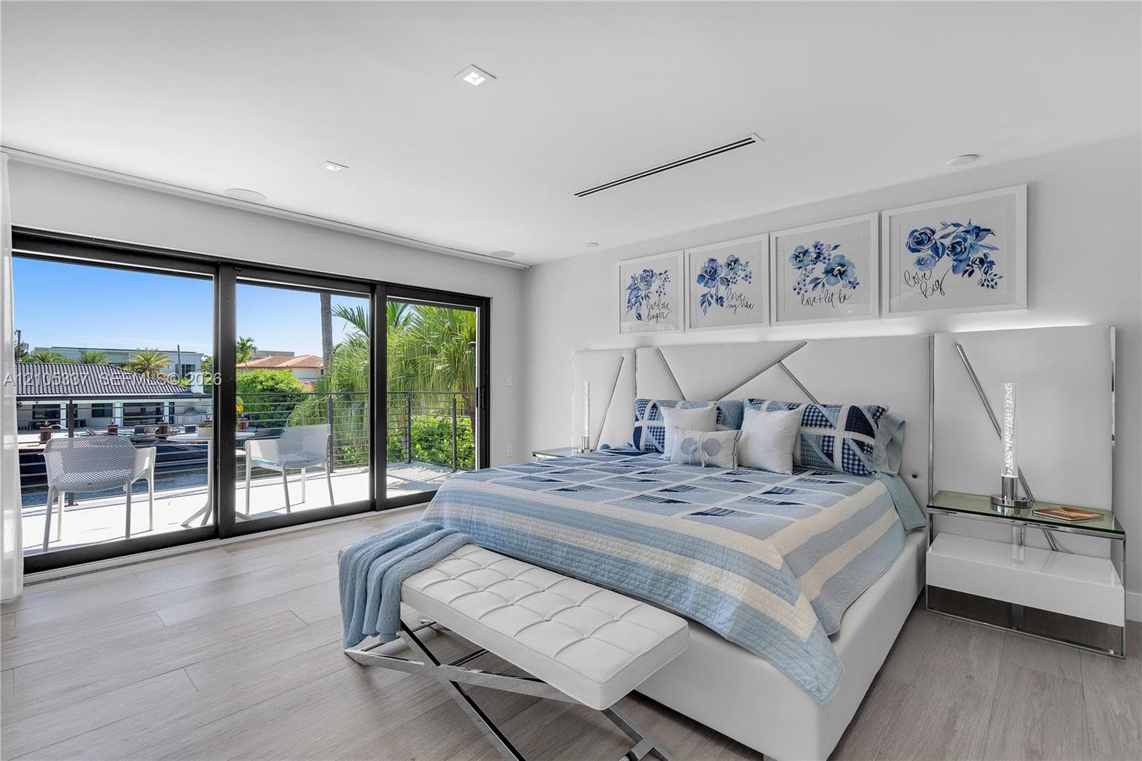 Sliding glass wall panels opening to an outdoor balcony, wood-finish flooring, recessed ceiling lighting, and a built-in linear ceiling fixture