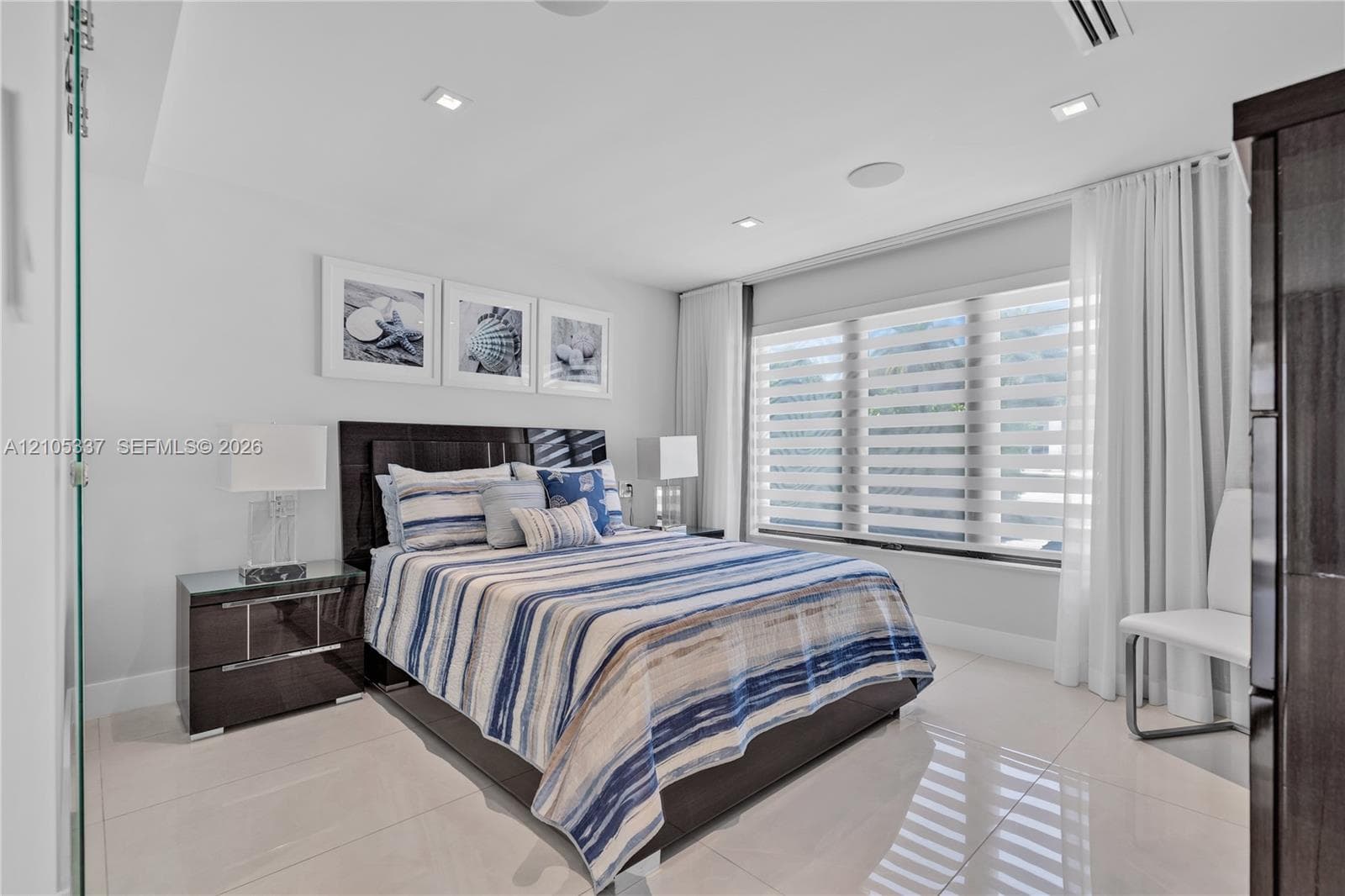 Neutral-toned porcelain tile flooring, recessed ceiling lighting, and large windows with horizontal banded shades