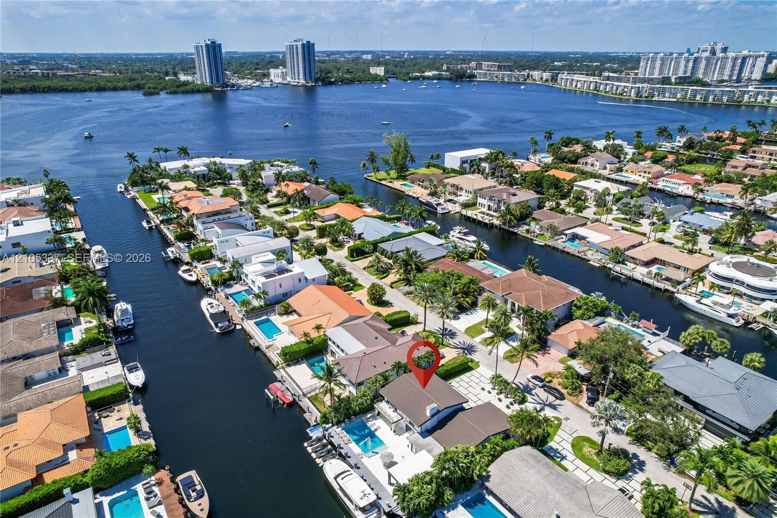Waterfront property featuring a private swimming pool, concrete bulkhead, boat dock, and expansive hardscaped patio