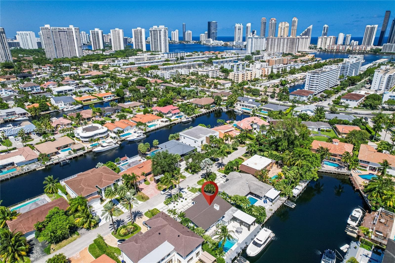 Waterfront property featuring a private boat dock, swimming pool, tiled patio, and shingled roof