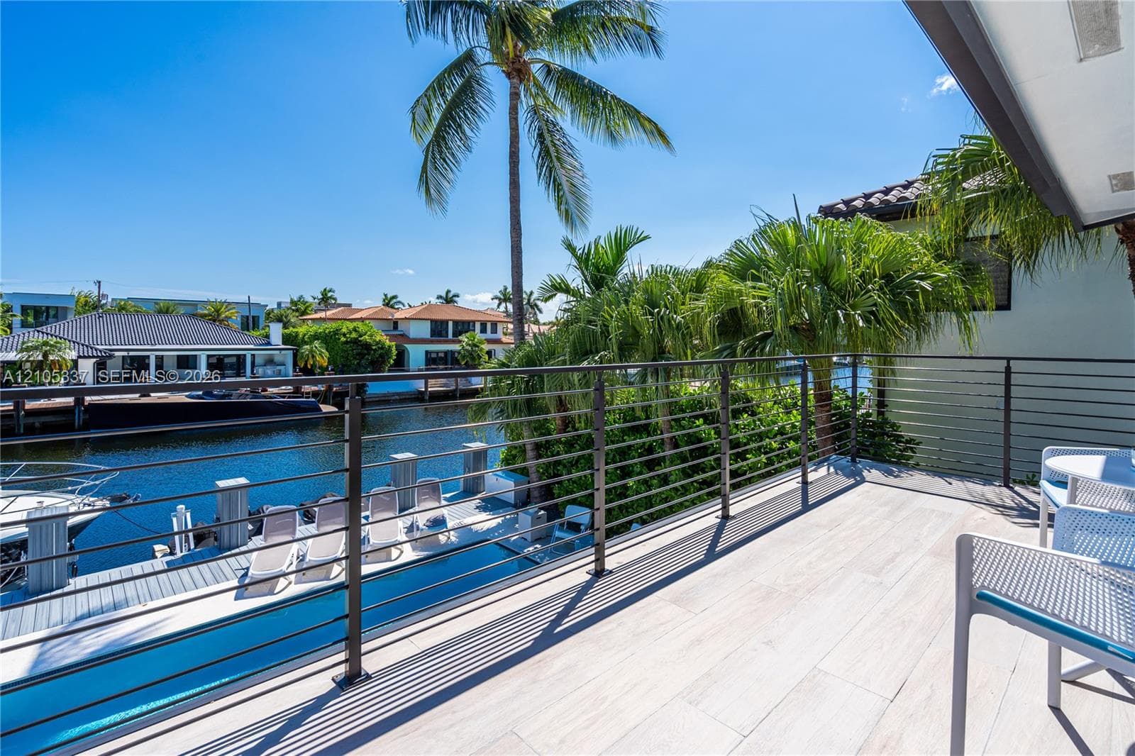 Elevated balcony featuring large-format porcelain tile flooring and horizontal cable railing system, overlooking a private dock and deep-water canal