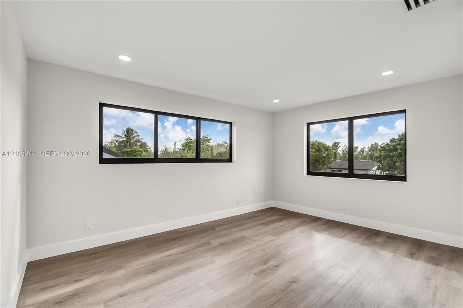 Interior space featuring wood-finish flooring, neutral wall paint, recessed lighting, and horizontal windows with black frames
