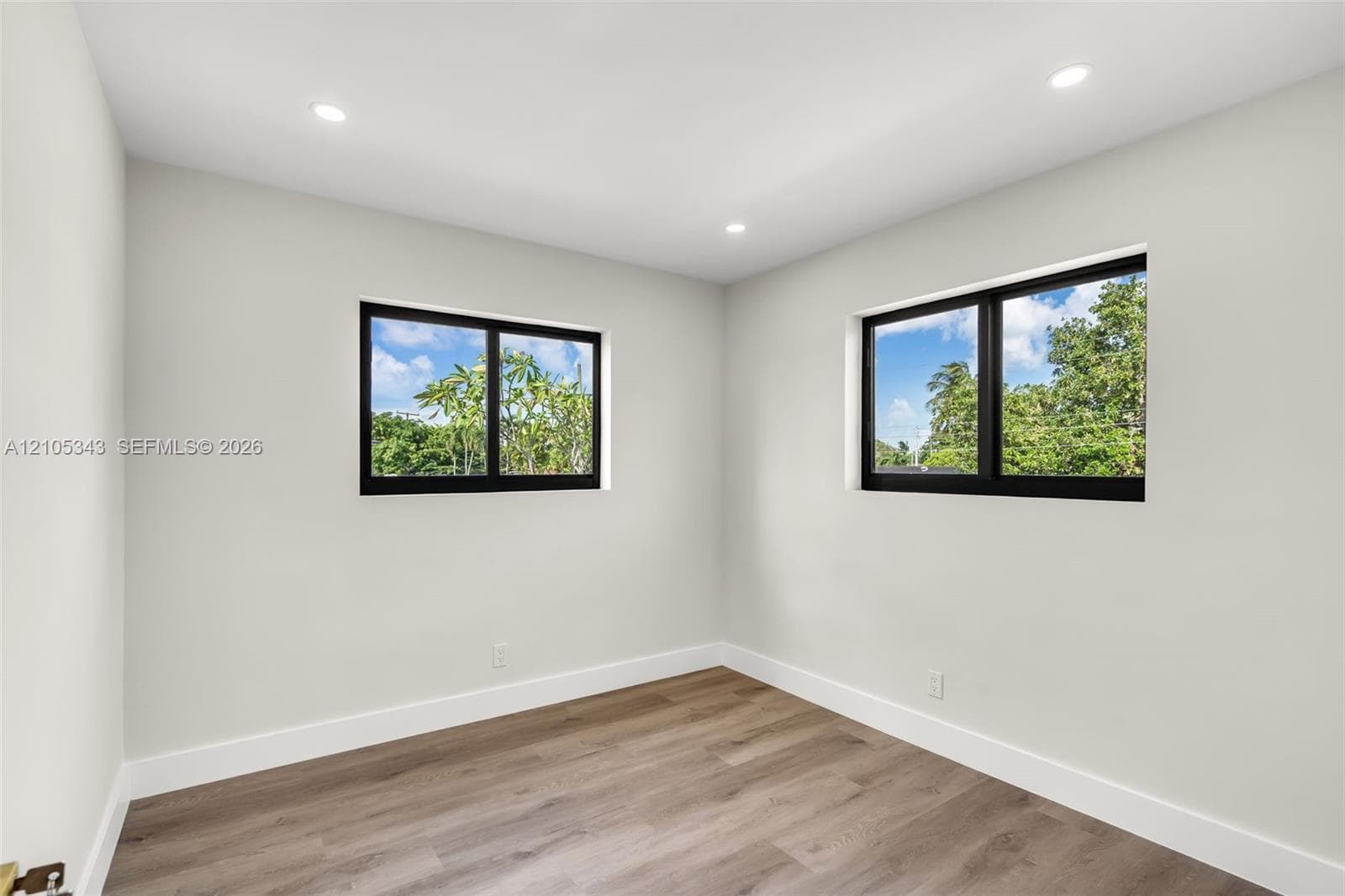 Neutral wall palette featuring wood-finish flooring, recessed lighting, and dual windows with black frames