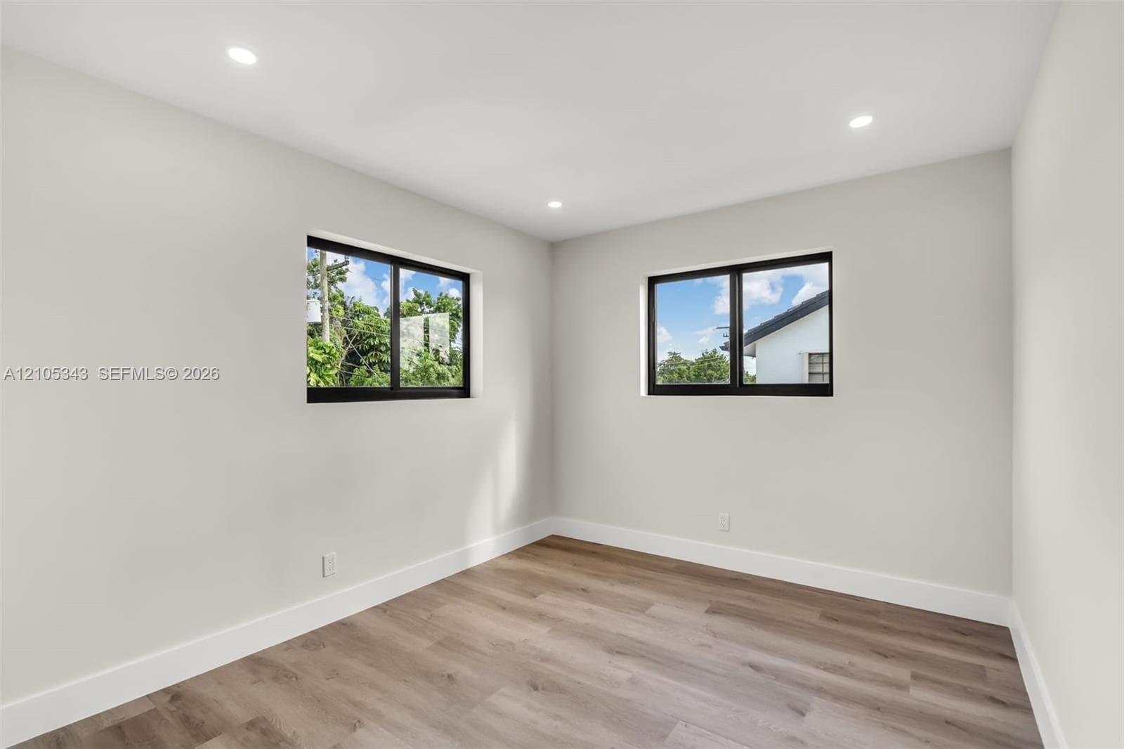 Interior space featuring wood-finish flooring, neutral wall tones, recessed lighting, and dual windows with black frames
