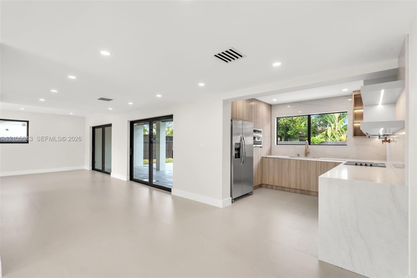 Open-concept interior featuring large-format tile flooring, recessed lighting, and sliding glass doors