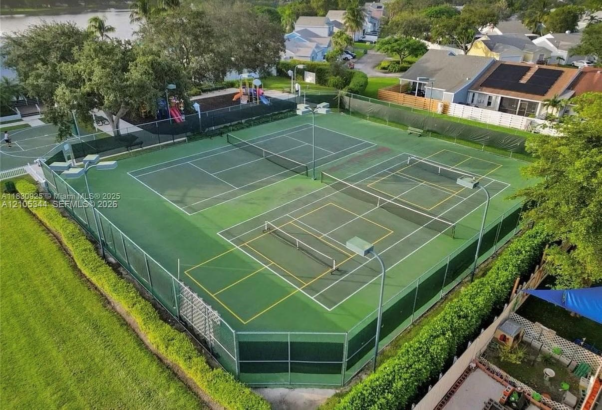 Multiple tennis and pickleball courts with perimeter fencing and integrated lighting