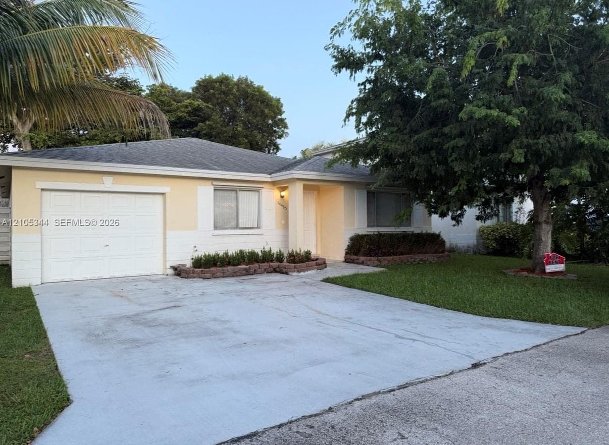 Single-story residence with a paved driveway, attached garage, and mature landscaping