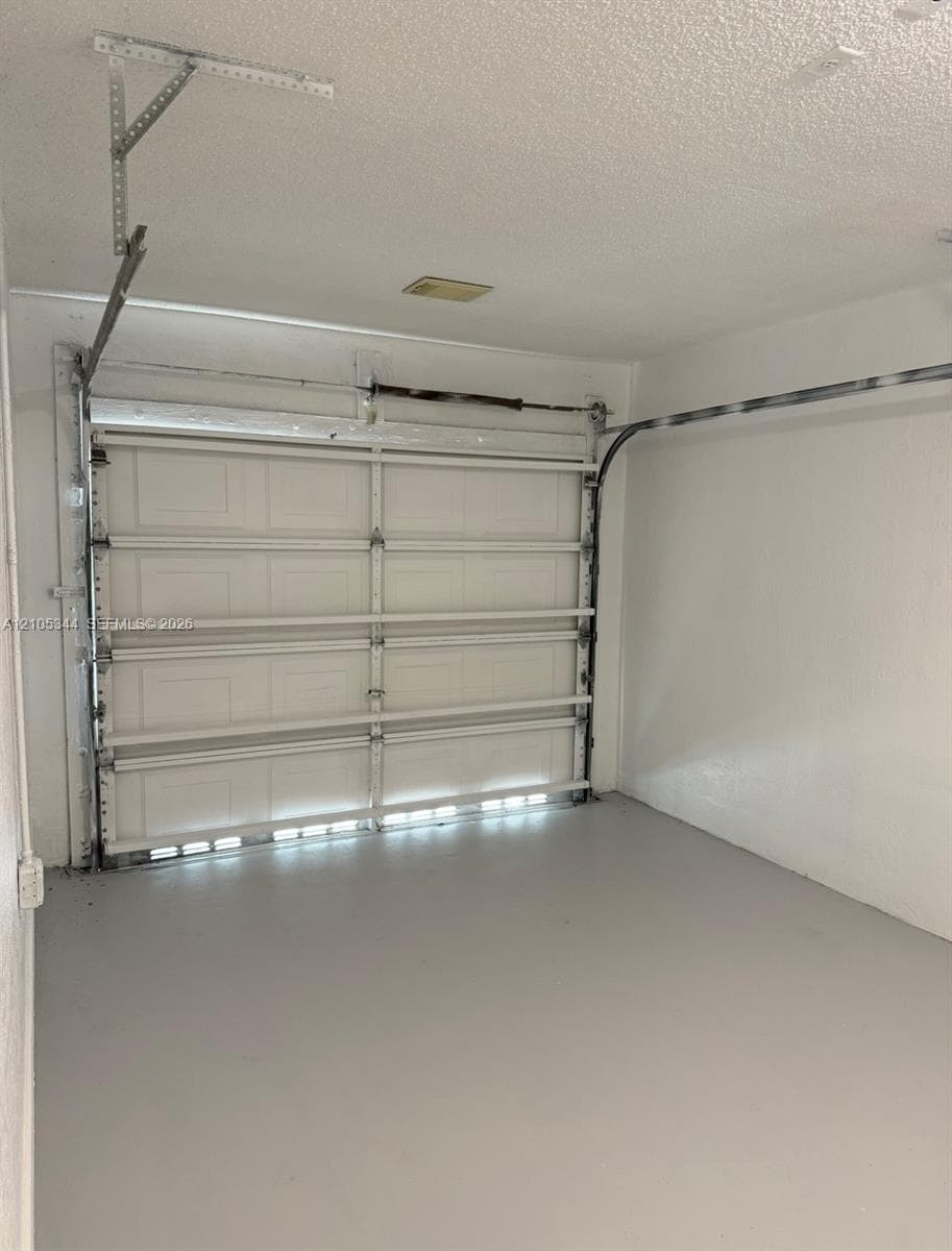 Attached garage featuring a light gray epoxy floor and a white paneled garage door