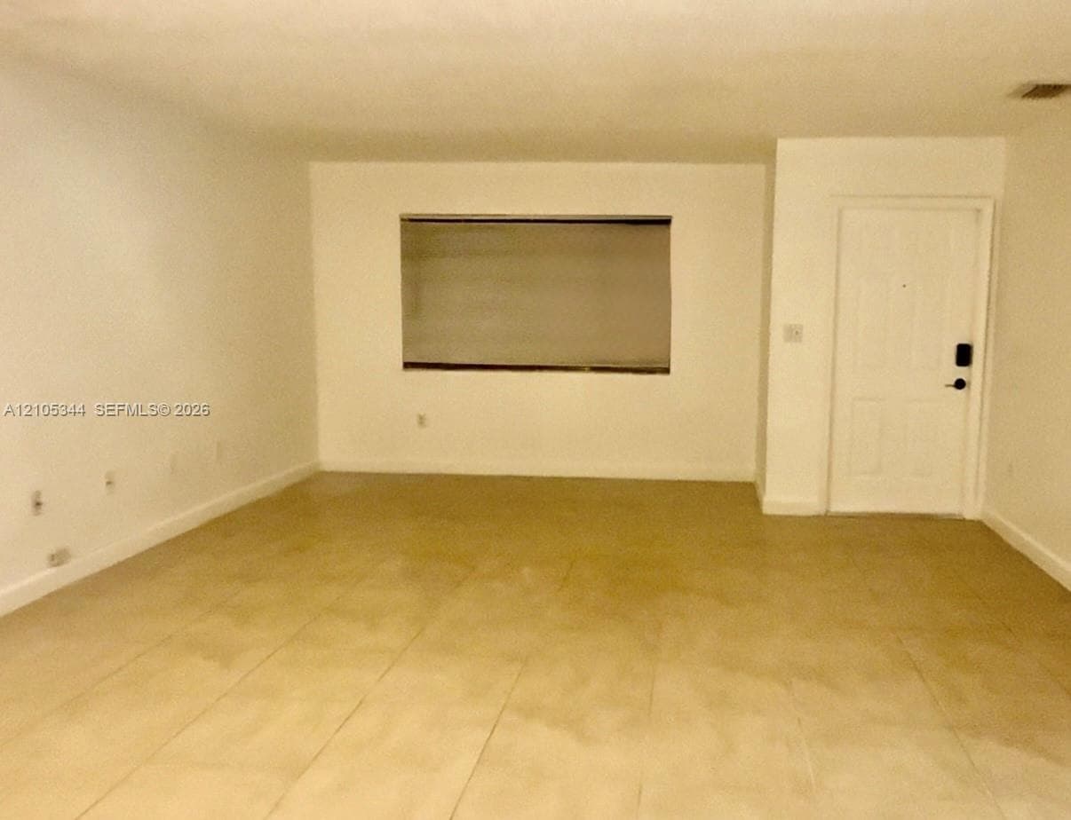 Spacious interior room featuring tile flooring, recessed lighting, and a wall-mounted window with horizontal blinds