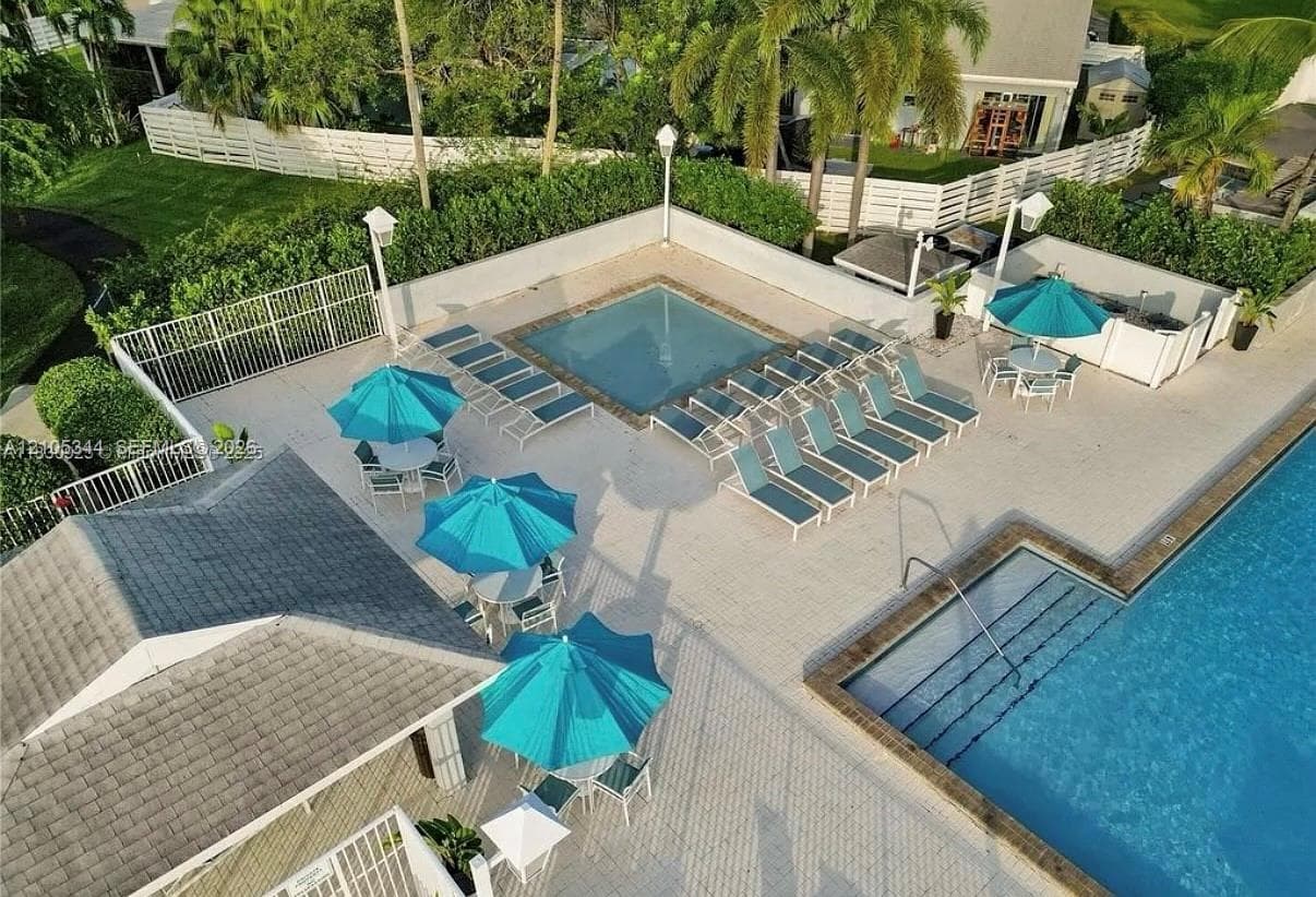Resort-style pool area featuring a large swimming pool, separate spa, and expansive paved patio
