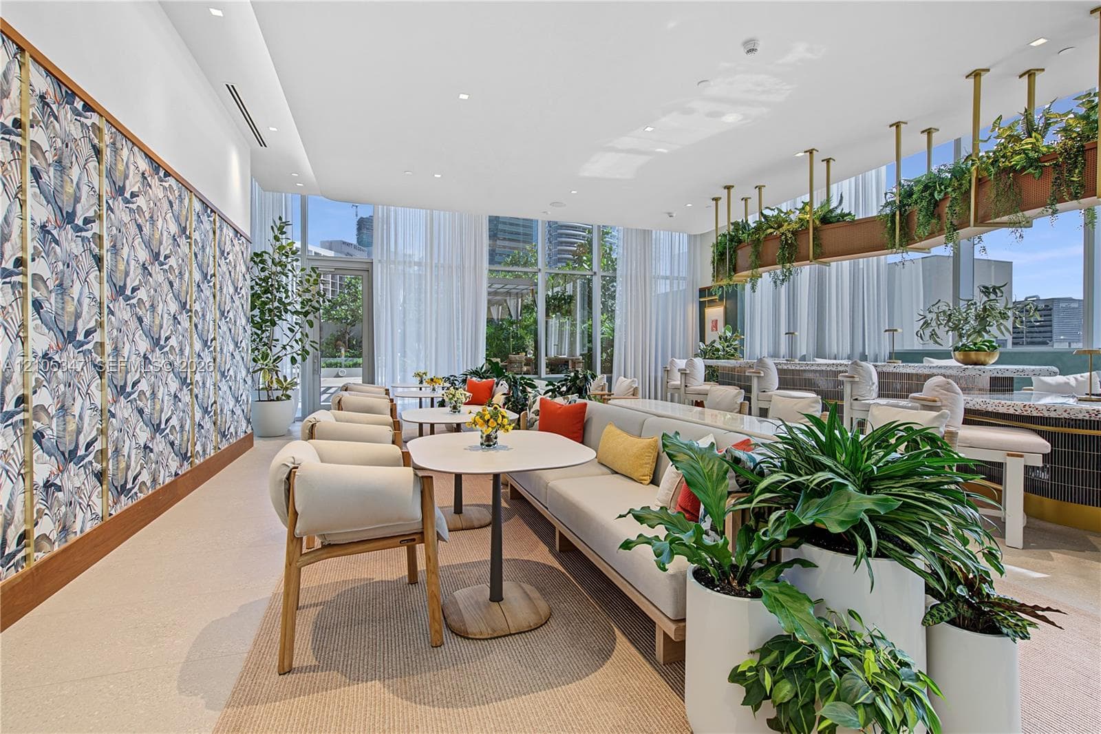 Common area featuring floor-to-ceiling windows, patterned wall covering with brass trim, a built-in stone-top bar, and suspended metal shelving
