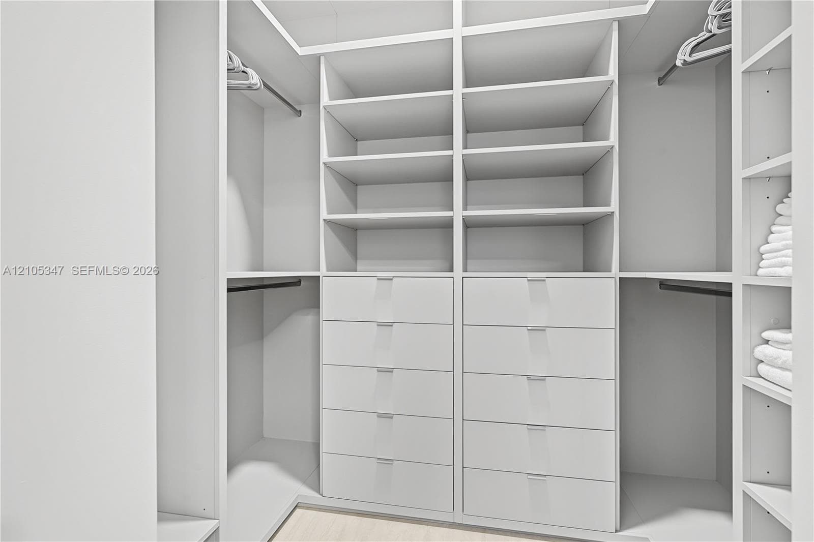 Custom closet system featuring integrated shelving, multiple hanging rods, and built-in drawer storage