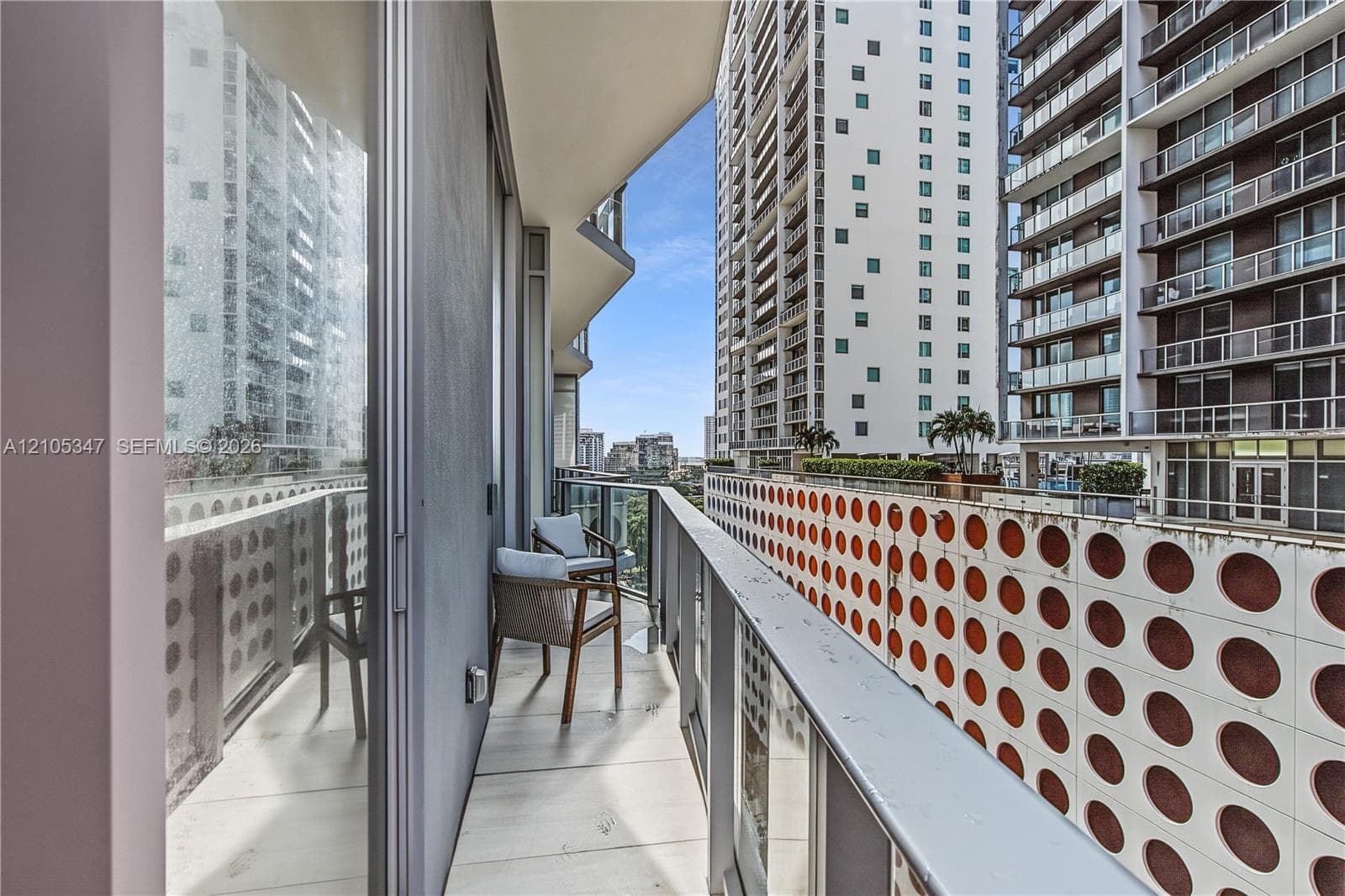 Private balcony with a light-toned flooring, glass and metal railing, and a sliding glass door