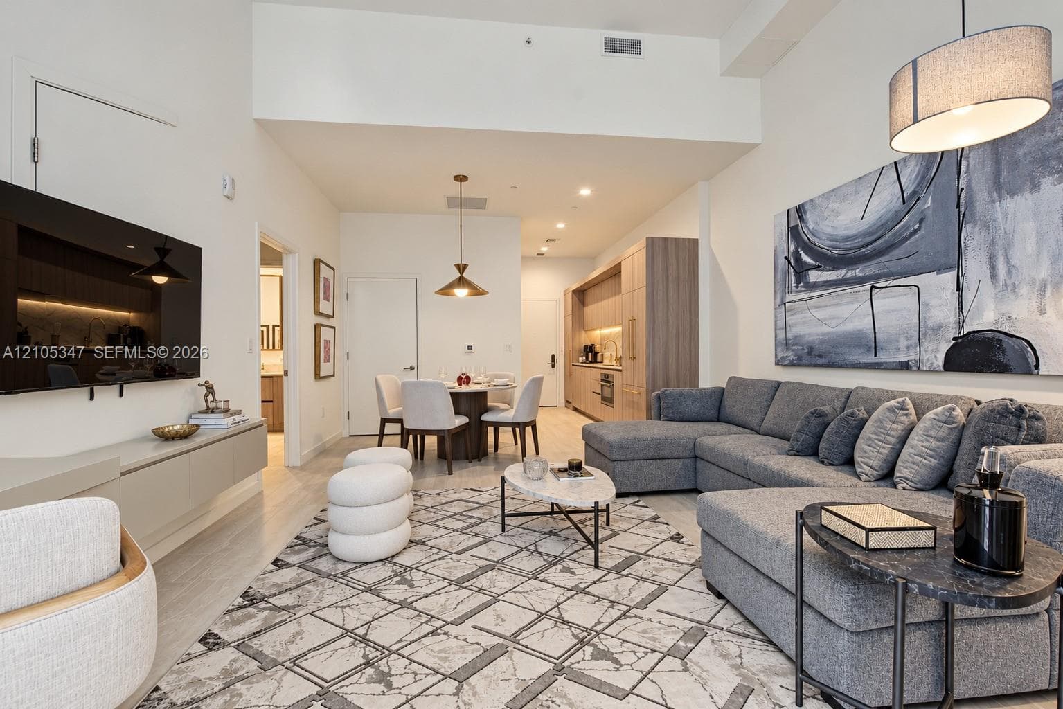 Vaulted ceiling, wood-finish flooring, built-in media console, recessed lighting, and a modern kitchen with built-in appliances