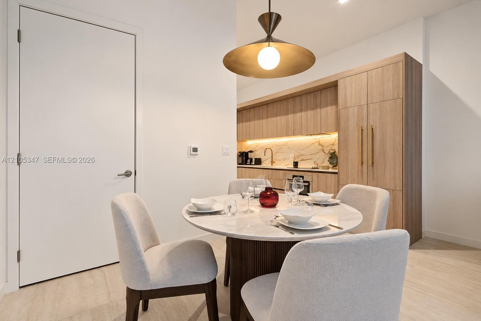 Integrated dining space featuring a round white marble-finish table and a contemporary ceiling fixture