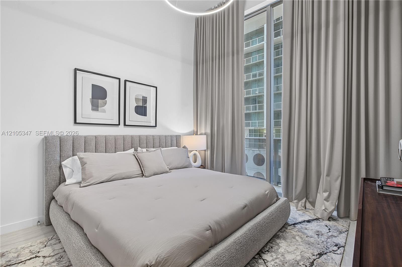 Floor-to-ceiling sliding glass doors, full-height drapery, wood-finish flooring, and a contemporary ceiling light fixture